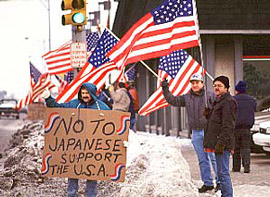 多くの星条旗がたなびくもとで、米国の自動車産業労働者たちが日本車輸入への反対を訴えています。