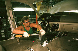 A woman works on a car interior  on assembly line