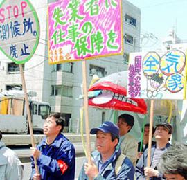 東京で開かれたメーデーで、プラカードを掲げた労働者たちがデモ行進しています。