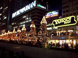 Neon signs and brightly lit Christmas trees illuminate a Tokyo street
