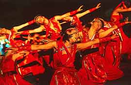 Dancers pose in unision, all wearing matching red outfits
