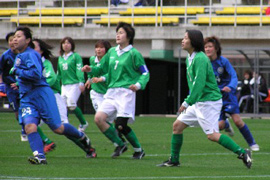 Two women's soccer teams playing a game, one team in blue, the other in green