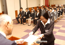 A woman receives a piece of paper from an older man, while others look on