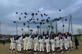 A baseball team, gathered in a circle, throws their hats into the air