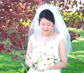 A bride sits, looking at her bouquet