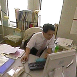 自分の机の上のコンピューターモニターに見入っている管理職の男性です。