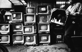 Man stacks televisions in a plie