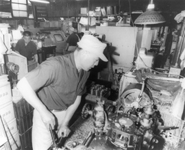 Man in a small space in factory works on a machine