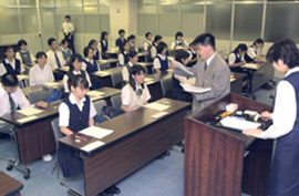 High school students in various unifroms receive an exam from a man in a suit