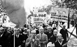 Men in bandana's march and cheer while holding signs