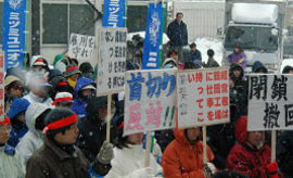 雪の中、プラカードを持った労働者たちがデモ行進しています。
