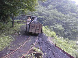 A man puts coal into wooden coal cart on train tracks
