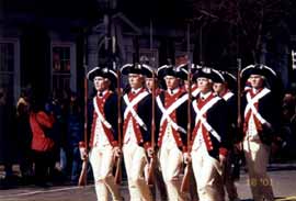 10人ほどの白人男性が、紺、白、赤を基調とした衣装に身を包み、銃剣をもって行進しています。