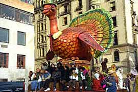 赤い体に緑や黄色で飾られた羽根をつけた大きなくじゃくの人形が街中をパレードしています。