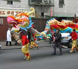 色鮮やかな布で作られた獅子を持ち、赤と金色の衣装の男性たちが街で獅子舞を披露しています。
