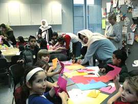 布で頭部を巻いたイスラム教徒の女性たちが小学校に招かれ、子供達と話をしています。