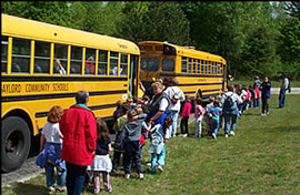 黄色いスクールバスの外に、子供達が並んでいます。