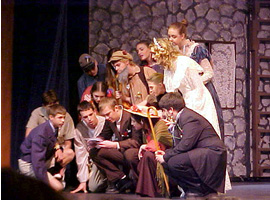 衣装をまとった学生達が舞台の上で演劇をしています。