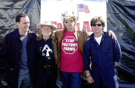 Four famous musicians stand in front of a tarp.