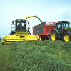 Two large tractors work in tandem in a field.