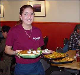 A waitress, holding several plates, smiles