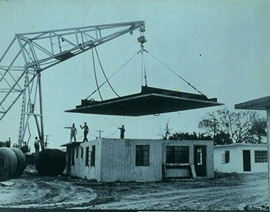 A crane lowers the roof onto a home being built