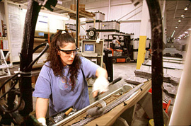 目を保護する大きな眼鏡をかけた女性が白い手袋をはめ、自動車組み立て工場で働いています。