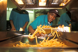 A  worker scoops fries at a fast food restaurant